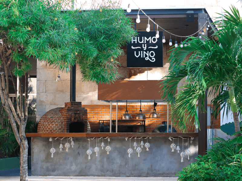 Outdoor bar Humo y Vino with a brick oven and greenery.